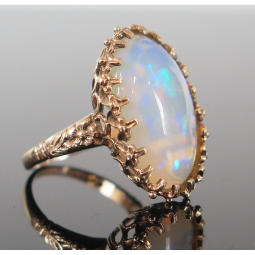 136 - 9ct Gold and White Opal Dress Ring, the c. 21.5x14.5mm singlet stone with a deep range of green, blu... 