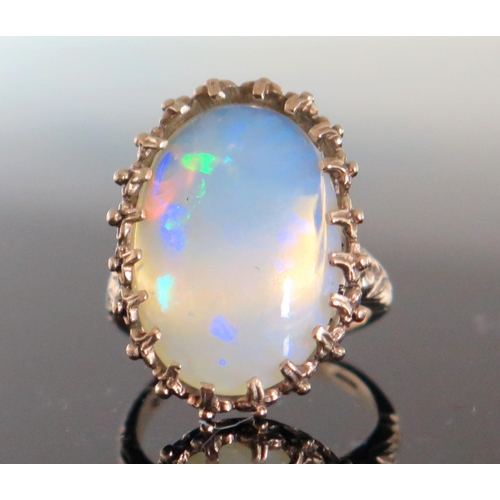 136 - 9ct Gold and White Opal Dress Ring, the c. 21.5x14.5mm singlet stone with a deep range of green, blu... 