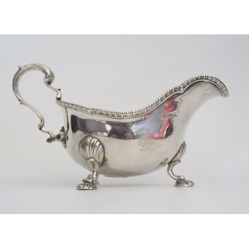 530 - A George III silver sauce boat, with gadrooned rim, high C scroll handle on three shell capped cabri... 