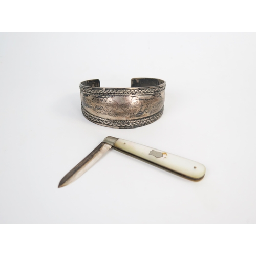 594 - A silver and mother of pearl fruit knife and a white metal cuff, (2).