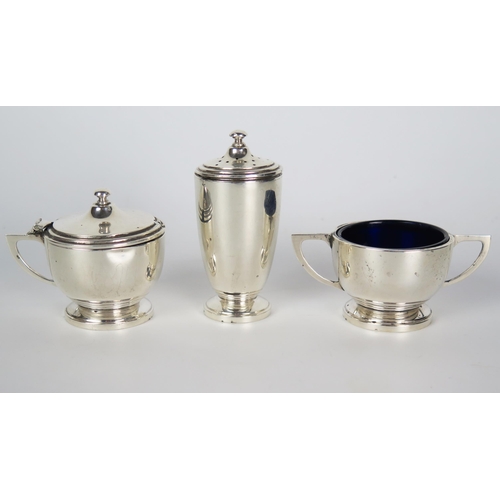 608 - An Art Deco three piece silver cruet set, comprising of a two handle salt with blue glass liner, mus... 