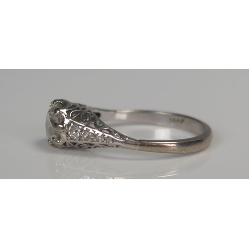 98A - 18ct White Gold and Diamond Solitaire Ring in a pierced scroll setting and with four small diamonds ... 