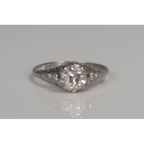 98A - 18ct White Gold and Diamond Solitaire Ring in a pierced scroll setting and with four small diamonds ... 