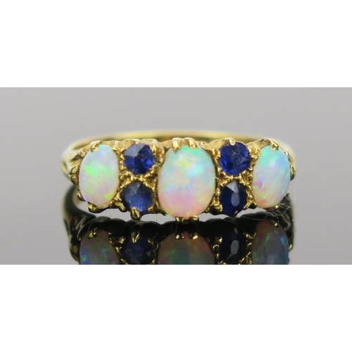 21 - White Opal and Sapphire Ring in an 18ct hallmarked gold setting, 17mm head, size K.75, Birmingham 19... 