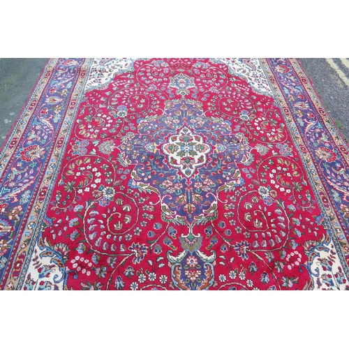 410 - A 20th Century Kashan style wool carpet, blue central medallion, red field, cream spandrels, blue bo... 