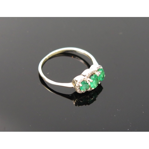 1007 - A mid 20th Century Emerald three stone ring, the central emerald 5x4mm flanked by two smaller, surro... 