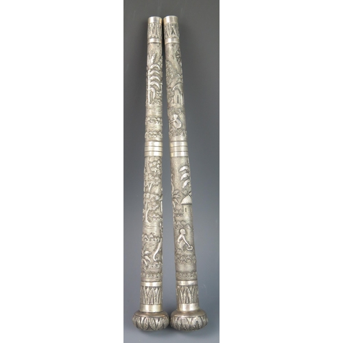 1172 - A pair of Indian silver parasol handles, decorated with figures in village surroundings, having pomm... 