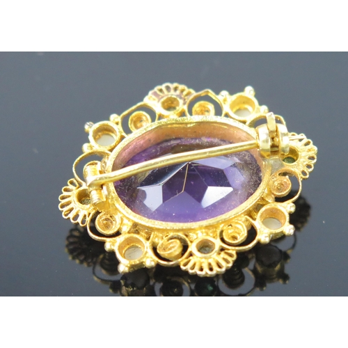 932 - An Antique Amethyst and Filigree Pendant Brooch, the oval stone 15x10mm, with greenstones and untest... 