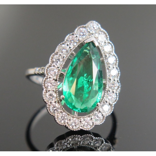 950 - An Emerald and Diamond Ring, the pear shaped emerald 15x8mm approximately, surrounded by twenty whit... 