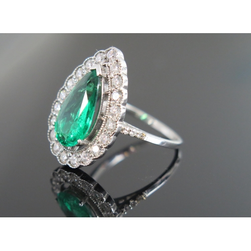 950 - An Emerald and Diamond Ring, the pear shaped emerald 15x8mm approximately, surrounded by twenty whit... 