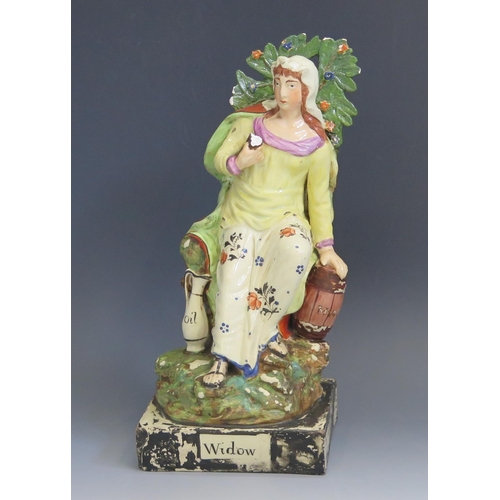 1257 - A Staffordshire pottery pearlware figure 'Widow' 26cm high.
Chips to the foliage and loss of painted... 