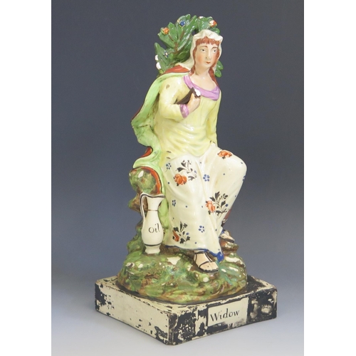 1257 - A Staffordshire pottery pearlware figure 'Widow' 26cm high.
Chips to the foliage and loss of painted... 