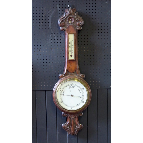 1126 - A late Victorian/Edwardian oak aneroid barometer  mounted on a onion topped case with foliate and sc... 