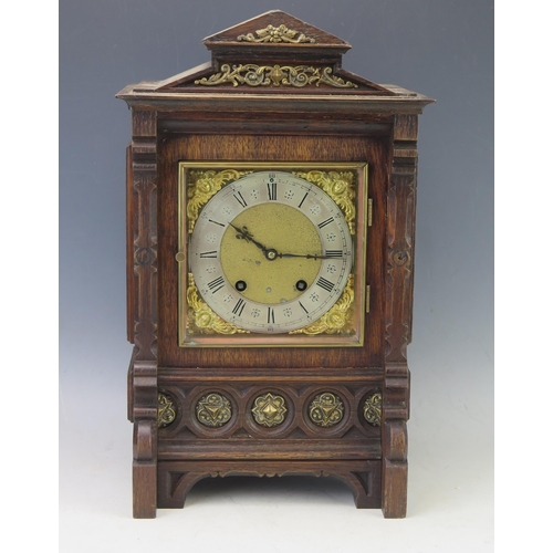 1128 - An oak cased mantel clock of architectural outline, with 16cm square brass dial and silvered Roman c... 