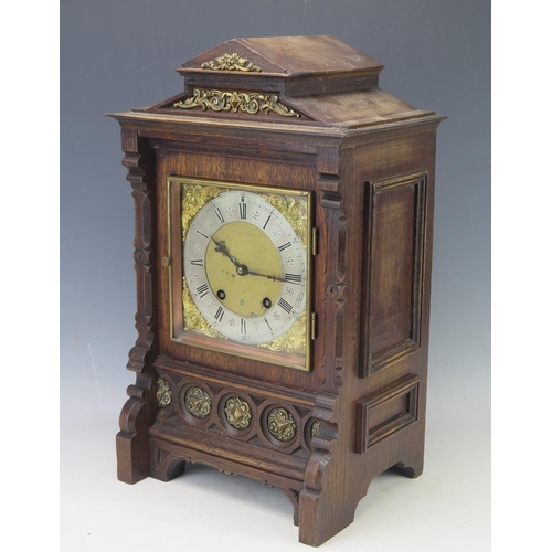 1128 - An oak cased mantel clock of architectural outline, with 16cm square brass dial and silvered Roman c... 