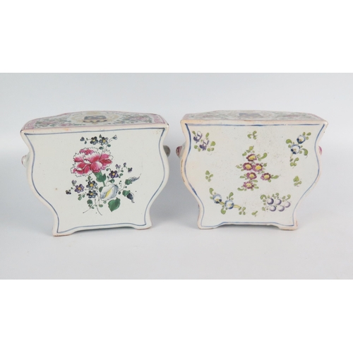 1245 - A pair of faience commodes of bombe-shaped outline, the tops bearing armorials enclosed by floral sp... 