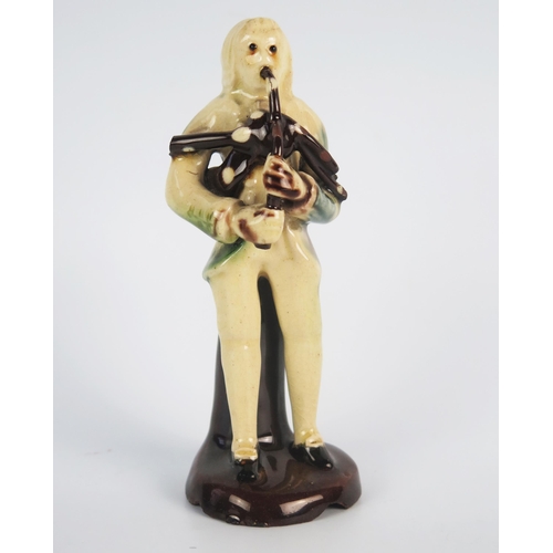 1246 - An 18th century Astbury-Whieldon pottery figure of a piper, with brown, blue and green treacle glaze... 