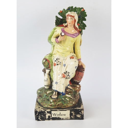 1257 - A Staffordshire pottery pearlware figure 'Widow' 26cm high.
Chips to the foliage and loss of painted... 