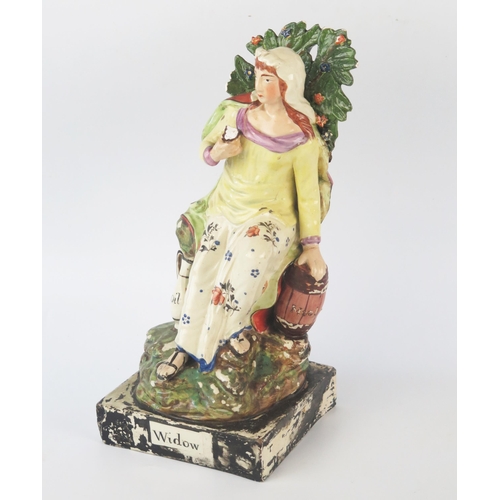 1257 - A Staffordshire pottery pearlware figure 'Widow' 26cm high.
Chips to the foliage and loss of painted... 