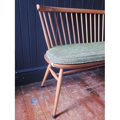 1324 - An Ercol love seat, the spindle back with cowhorn top rail, the solid seat with chamfered and wavy e... 