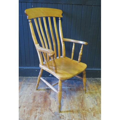 1333 - A beech Windsor style elbow chair, with slatted back, solid seat, on ring turned legs linked by stre... 