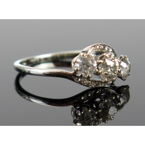 162 - A Three Stone Diamond Crossover Ring in an unmarked precious white metal setting, the old cuts estim... 