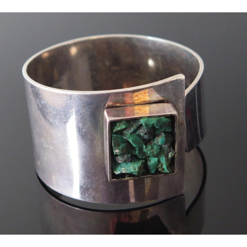 207 - A 1970's Danish Silver Bangle with a raised square reserve filled with green stone, signed WIGGERS, ... 