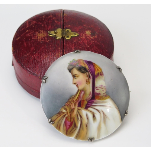 218 - A 19th Century Continental Porcelain Brooch decorated with a hand painted figure of a lady in profil... 