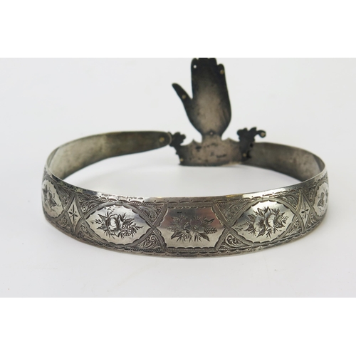 582 - A silver collar, unmarked, the band with chased floral decoration, the link in the form of a family ... 