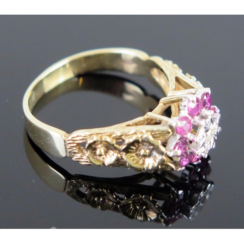 62 - A 9ct Gold Ruby and Diamond Cluster Ring with pierced floral decorated shoulders, c. 12mm wide head,... 