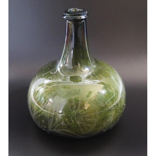 1287 - An early 18th century green glass wine bottle of onion shaped outline with scratched decoration of f... 