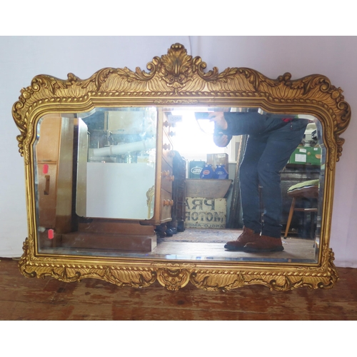 1309A - A gilt framed mirror, the shaped bevelled mirror plate enclosed by an arched frame with scroll and f... 