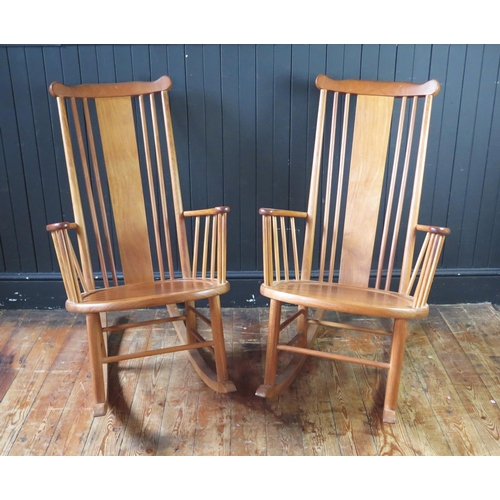 1340 - A pair of teak rocking chairs with solid central splat and spindle back with solid seat on rocker su... 