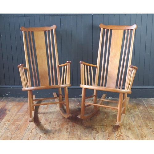 1340 - A pair of teak rocking chairs with solid central splat and spindle back with solid seat on rocker su... 