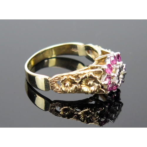 211 - A 9ct Gold Ruby and Diamond Cluster Ring with pierced floral decorated shoulders, c. 12mm wide head,... 