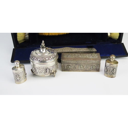 773 - An Indian silver dressing table set, decorated with dancing figures, includes trinket boxes, scent b... 