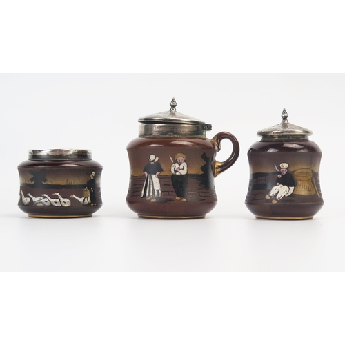 1334 - Taylor Tunnicliffe & Co., a pottery and silver mounted three-piece condiment set, with painted Dutch... 