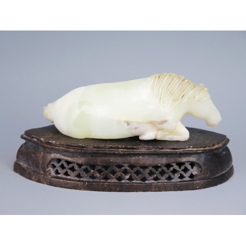 1436 - A Chinese carved jade figure of a recumbent horse, 9.5cm long, on a polished hardstone stand.