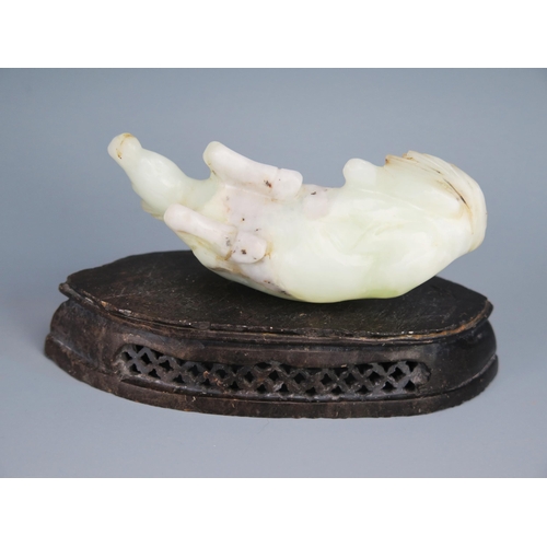 1436 - A Chinese carved jade figure of a recumbent horse, 9.5cm long, on a polished hardstone stand.