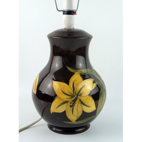 1369 - A Moorcroft pottery table lamp. the dark brown ovoid body decorated with yellow Bermuda lilies, 28cm... 