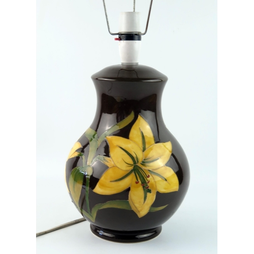 1369 - A Moorcroft pottery table lamp. the dark brown ovoid body decorated with yellow Bermuda lilies, 28cm... 