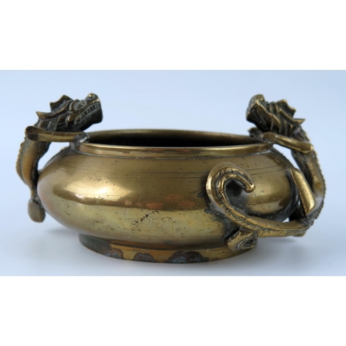 1415 - A Chinese bronze censer of squat circular form decorated with two dragons, holding the rim, bears ps... 