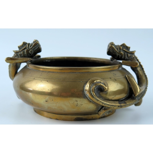 1415 - A Chinese bronze censer of squat circular form decorated with two dragons, holding the rim, bears ps... 