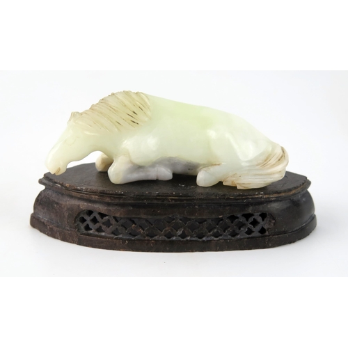 1436 - A Chinese carved jade figure of a recumbent horse, 9.5cm long, on a polished hardstone stand.