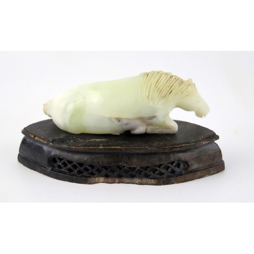 1436 - A Chinese carved jade figure of a recumbent horse, 9.5cm long, on a polished hardstone stand.