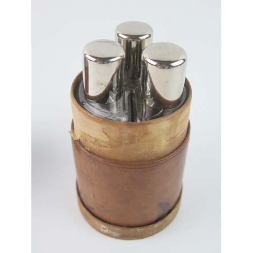 1626 - A nest of three clear glass scent bottles contained in a leather travelling canister.