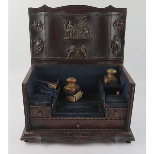 1655 - A continental oak writing box of serpentine outline, , the double hinged lid enclosing an arrangemen... 