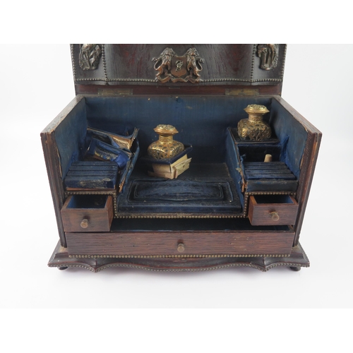 1655 - A continental oak writing box of serpentine outline, , the double hinged lid enclosing an arrangemen... 