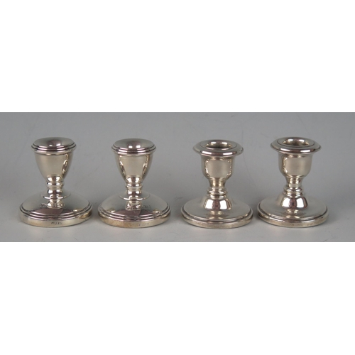 33 - Two pairs of miniature silver desk candle sticks, of traditional design with filled circualr bases, ... 