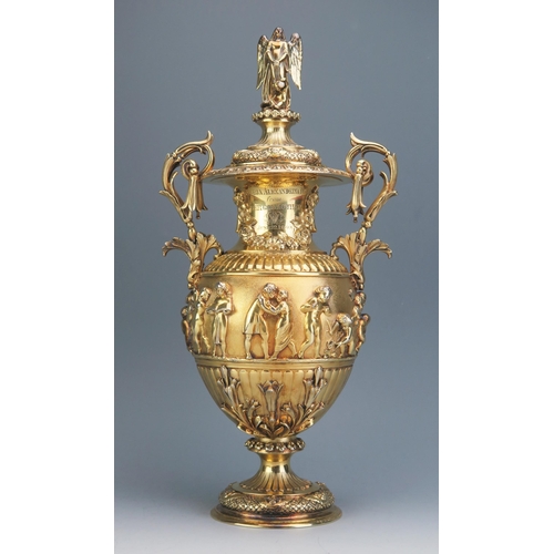 A ROYAL CHRISTENING PRESENT:- AN EARLY VICTORIAN SILVER-GILT CUP & COVER, maker John Mortimer & John Samuel Hunt, London, 1839, of part-fluted vase form with bifurcated scroll handles hung with pendent bell-flowers, the waisted neck applied with floral swags, the body with broad matted frieze decorated in high relief with children & playful putti, the lower body applied with foliage, on pedestal foot decorated with repetitive flower-heads & winged cherub masks, the cover similarly decorated below a fluted pedestal surmounted by a finial of an angel with attendant putto and inset pearl, engraved with Queen Victoria's crowned cypher & inscribed Victoria Alexandrina Digby  From Her Godmother VR, June 22, 1840, 37cm high. contained in its original leather and silk lined case bearing makers name. 2026gms, 65,16ozs.

Provenance; By family decent. Given by Queen Victoria to her goddaughter Victoria Alexandrina Digby on the occasion of her christening in 1840. Victoria was the daughter of Edward St. Vincent Digby
9th Baron Digby, she married in 1865, and died in Devon at the age of 77 in 1917.